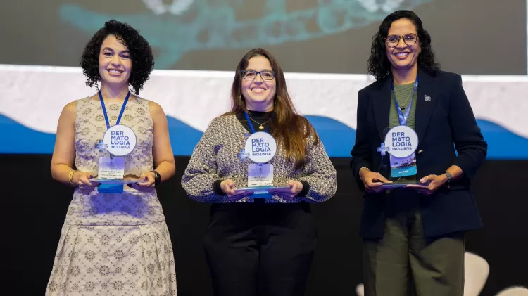 A imagem mostra 3 das quatro vencedoras do prêmio no palco do 35º Congresso Brasileiro de Cirurgia Dermatológica. Sandra está na ponta, do lado esquerdo.