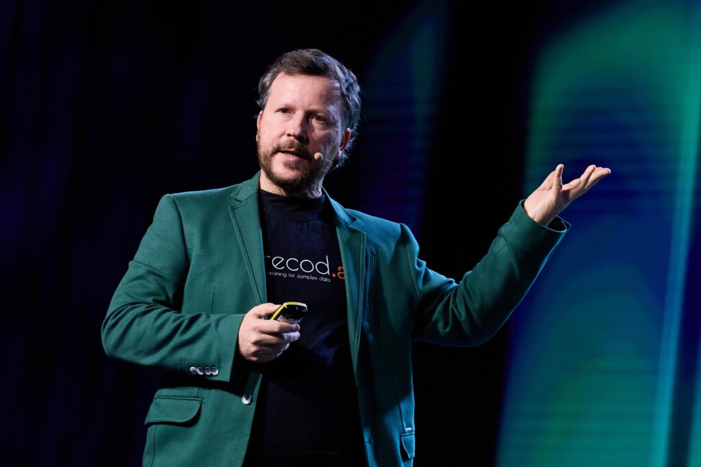 A imagem mostra Prof. Anderson Rocha do Instituto de Computação da Unicamp de blazer dando uma palestra